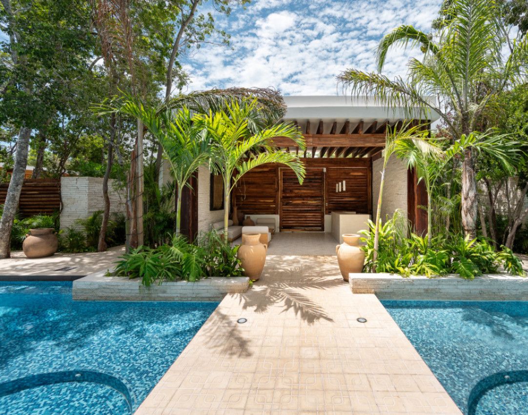 A pool area with a wooden deck, palm trees, and a building with a wooden facade.