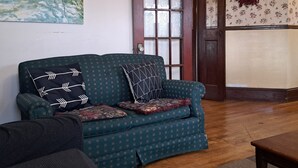 A living room with a patterned sofa, a painting on the wall, and a door with floral wallpaper. - Downtown heritage flat near everything (Dartmouth)