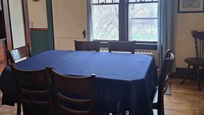A dining room with a large table, chairs, a chandelier, a clock, and windows with curtains. - Downtown heritage flat near everything (Dartmouth)