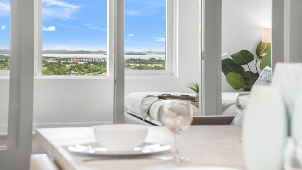 A modern hotel room with a large window offering a view of a bridge and greenery. - 1 Bedroom Private Residence at Roney Palace (Miami Beach)