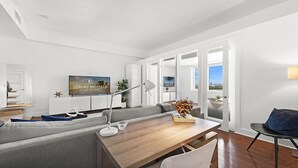 A modern living room with a grey sofa, wooden coffee table, and a TV displaying 'Luxury Rentals Miami Beach'. - 1 Bedroom Private Residence at Roney Palace (Miami Beach)