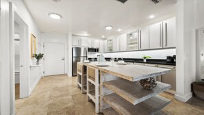A modern kitchen with white cabinetry, a wooden island, stainless steel appliances, and recessed ceiling lights. - 1 Bedroom Private Residence at Roney Palace (Miami Beach)