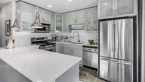 A modern kitchen with stainless steel appliances, white cabinetry, and a central island. - 2BR, 2BA Cozy, Central, Downtown Convention Center (Seattle)