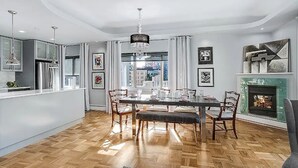 A modern kitchen with a dining area, featuring a chandelier, wooden flooring, and a fireplace. - 2BR, 2BA Cozy, Central, Downtown Convention Center (Seattle)