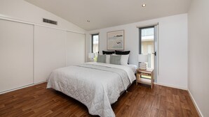 Un dormitorio con una cama grande, una mesita de noche, una ventana y una puerta.