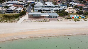 Vista aérea de una zona residencial costera con casas, una playa y un pequeño muelle.