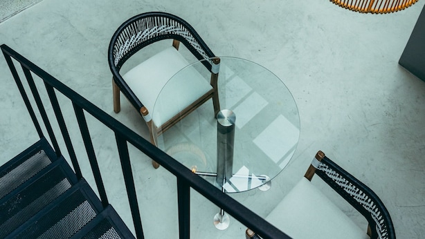 A modern interior with a glass table surrounded by wicker chairs, a staircase, and a hanging light fixture. - I Believe All Suite  (Medellín)