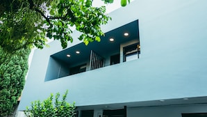 A modern building with a flat facade, recessed lighting, and a balcony with a metal railing. - I Believe All Suite  (Medellín)