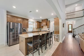 A spacious kitchen with a central island, stainless steel appliances, and wooden cabinetry.