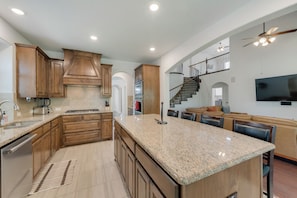 A spacious kitchen with granite countertops, wooden cabinets, and a central island.