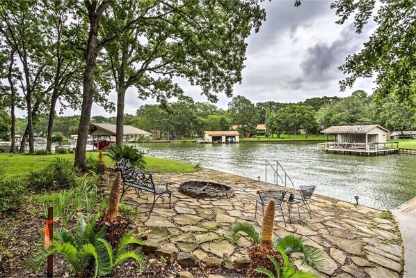 A lakeside patio with stone flooring, outdoor seating, and a fire pit. - Starlight Point — Panoramic Waterfront Retreat in Star Harbor, Cedar Creek Lake (Malakoff)