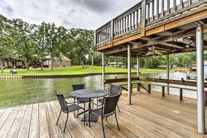 A wooden deck with a table and chairs overlooking a body of water, supported by metal columns. - Starlight Point — Panoramic Waterfront Retreat in Star Harbor, Cedar Creek Lake (Malakoff)