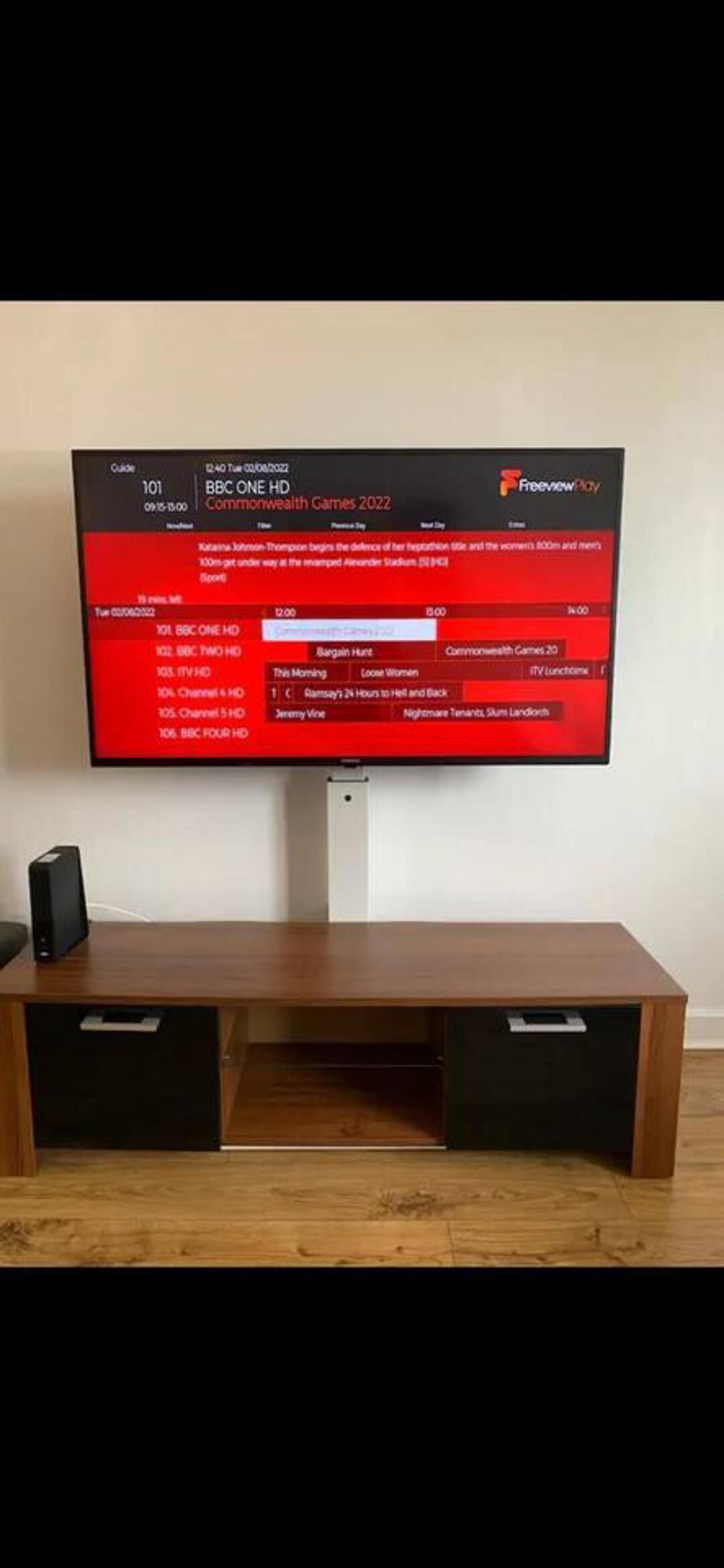 A flat-screen TV mounted on a wooden TV stand with two drawers.
