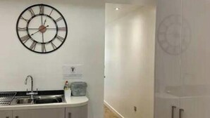 A modern kitchen with a built-in sink, a clock on the wall, and a cabinet with a handle. - Immaculate 2-bed Apartment in Leigh (Leigh)