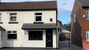 A two-story residential building with a flat roof, a front door, and a small porch. - Immaculate 2-bed Apartment in Leigh (Leigh)