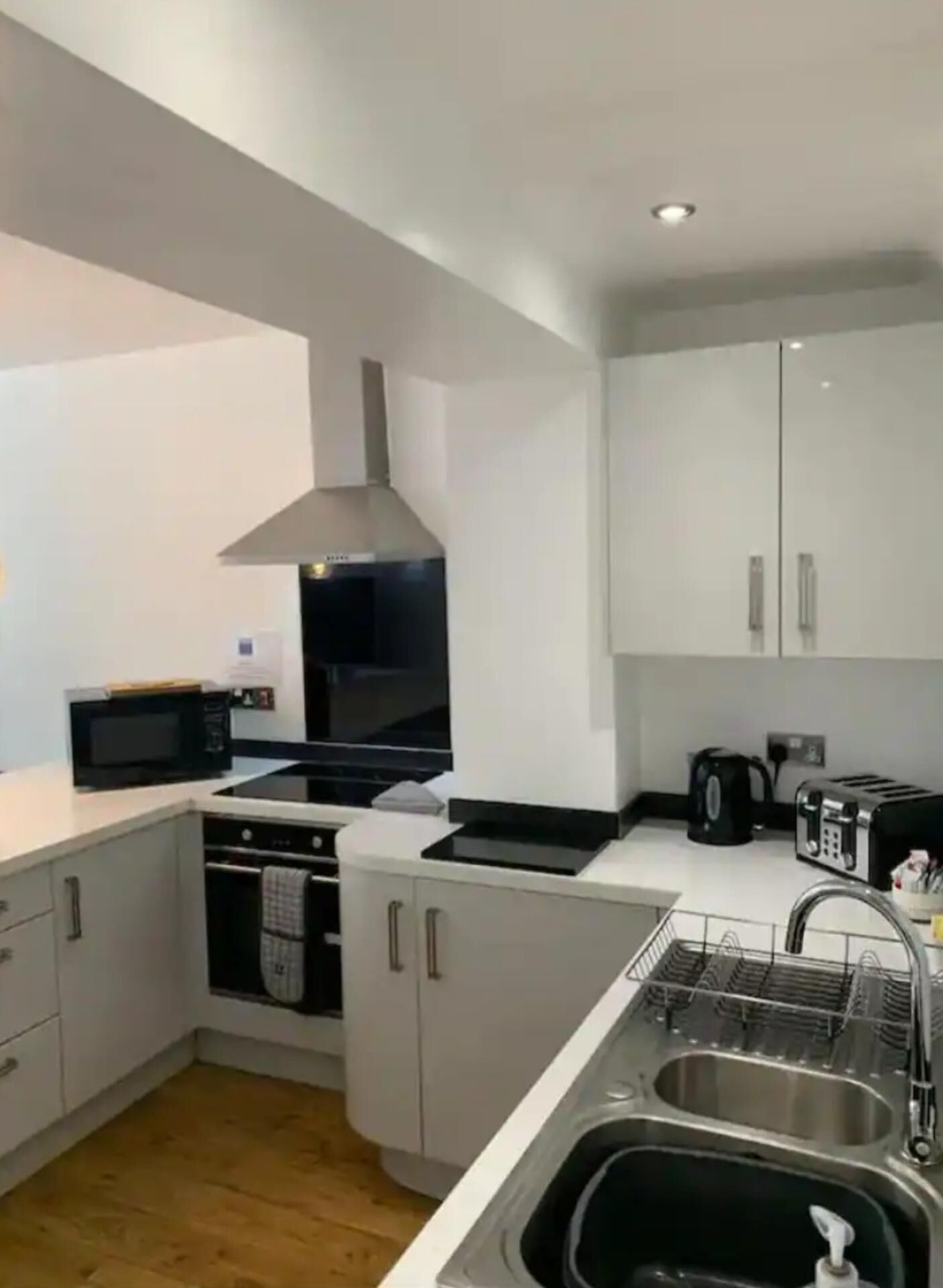 A modern kitchen with white cabinets, a microwave, a stove, and a sink.