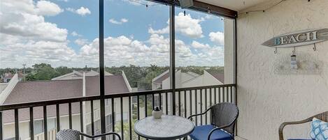 A balcony with a table and chairs, a ceiling fan, and a sign that says "BEACH".