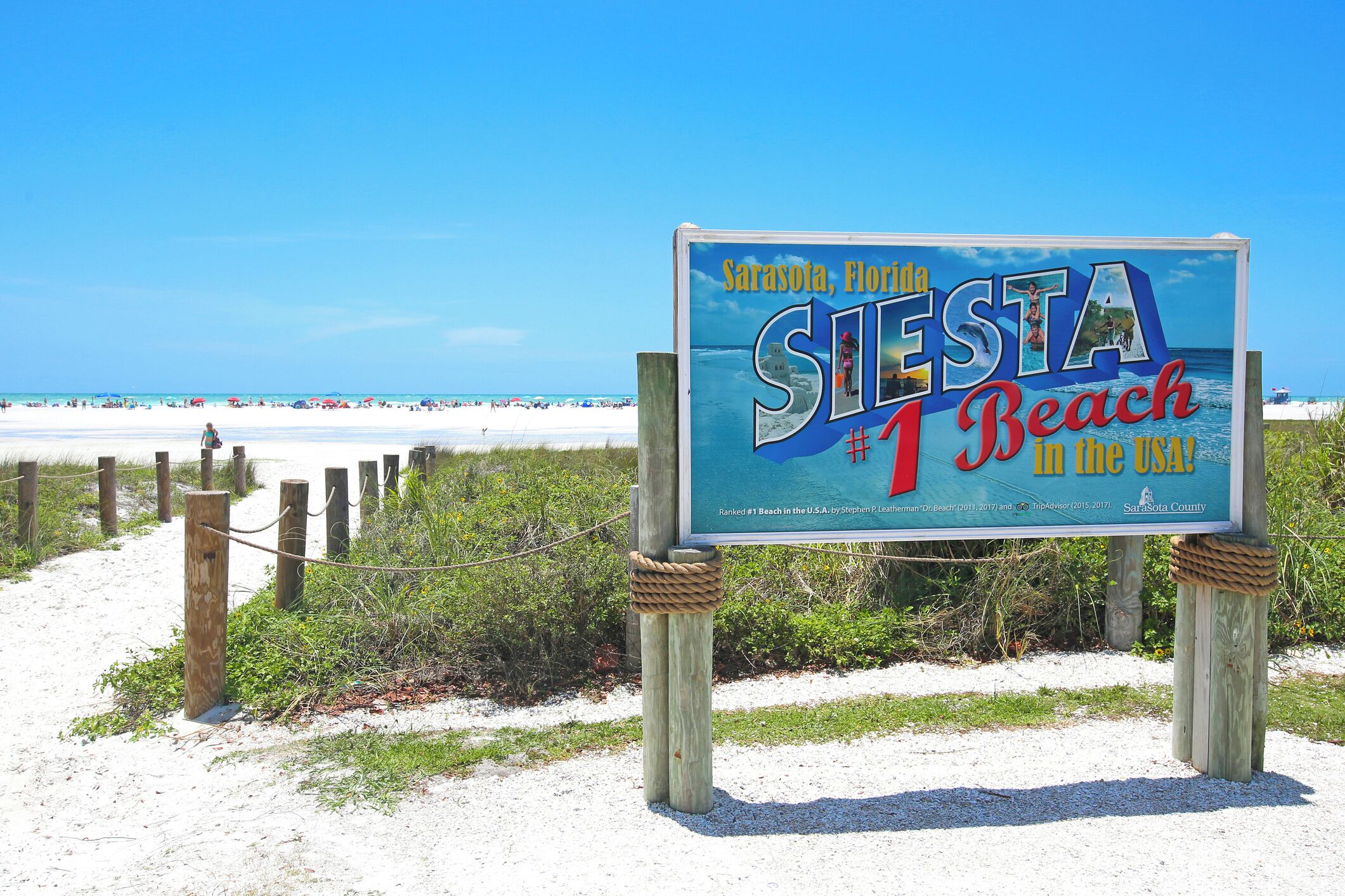 A beach sign with the text "Sarasota, Florida, Siesta Beach, #1 Beach in the USA!"