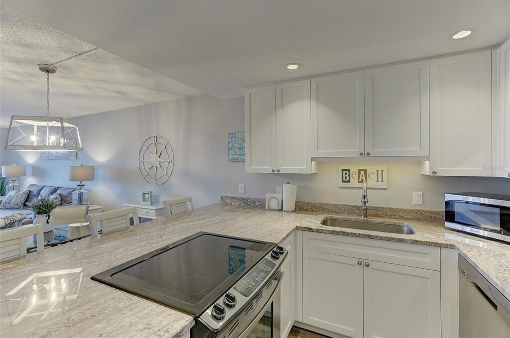 A modern kitchen with white cabinets, a built-in stove, and a microwave.