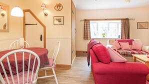 A cozy room with a dining table, chairs, a sofa, and a staircase. - White Cottage - UK7679 (Golspie)
