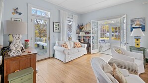 A spacious living room with a white sofa, a green cabinet, and a wooden floor. - Charming Coastal Biddeford Pool Home (Biddeford)