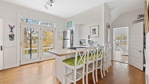 A spacious kitchen with a central island, white cabinetry, and a large window providing a view of the outdoors. - Charming Coastal Biddeford Pool Home (Biddeford)