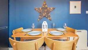 A dining area with a star-shaped light fixture, wooden chairs, and a table set for four. - 2 bedroom accommodation in Dornoch (Dornoch)