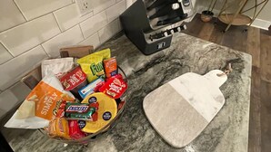 Keittiön työtaso, jonka päällä on kulho, jossa on erilaisia pikkupurtavia, sekä leikkuulauta.