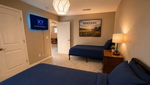 A hotel room with a large bed, a smaller bed, a TV, a Kentucky painting, and a lamp. - Modern 3BR Townhome Near Kentucky Horse Park | Georgetown, KY (Georgetown)