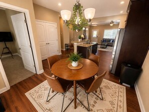 A dining area with a round table, chairs, and a chandelier.