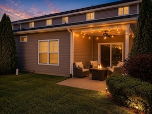 A residential building with a covered patio area featuring outdoor seating and string lights.
