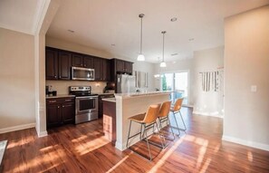 A modern kitchen with dark cabinets, stainless steel appliances, and a central island with bar stools.