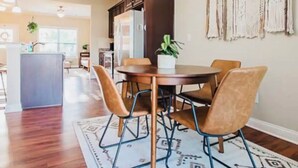 A dining area with a round table and chairs, a patterned rug, and a kitchen in the background. - Modern 3BR Townhome Near Kentucky Horse Park | Georgetown, KY (Georgetown)