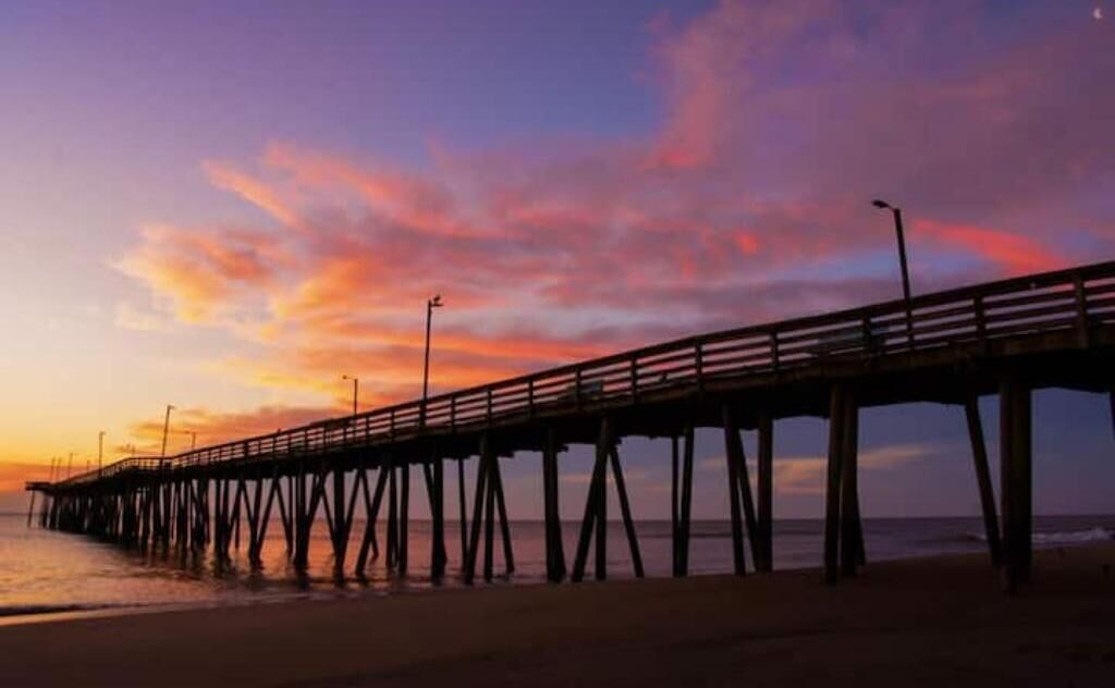 A pier extending into the water with a sunset in the background.