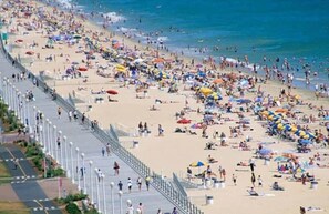 Ein überfüllter Strand mit vielen Sonnenschirmen und Menschen.