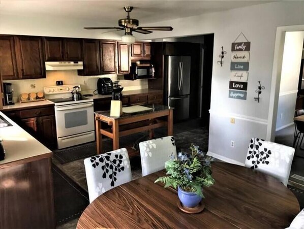 A modern kitchen with dark wood cabinets, stainless steel appliances, and a dining area with a wooden table and chairs.