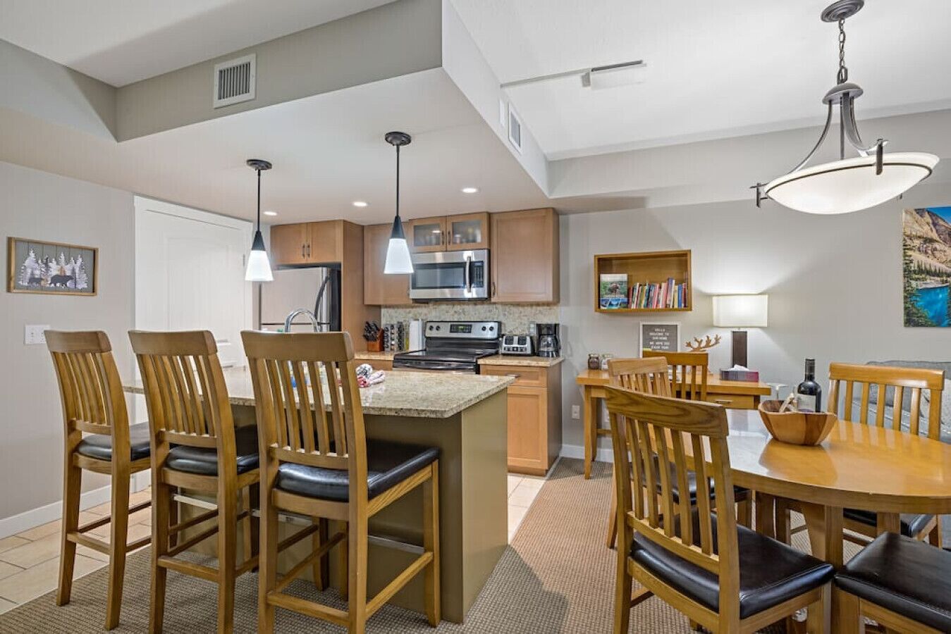 Een moderne keuken met houten kastjes, een centraal eiland en hangende lampen.