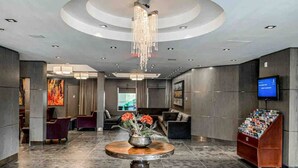 A modern lobby with a round table, seating area, and a television on the wall.