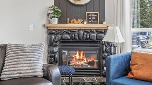 Un salon chaleureux avec une cheminée en pierre, une cheminée en bois et une pancarte accueillante.