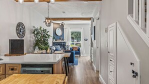 Une cuisine moderne dotée d’un îlot central, de poutres en bois et d’un coin repas avec un canapé bleu.