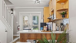 Une cuisine moderne avec des meubles en bois, un plan de travail blanc et une vue sur l’extérieur.