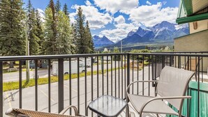 Un balcon avec vue sur les montagnes, un espace de stationnement et un bâtiment doté d’un toit végétalisé.