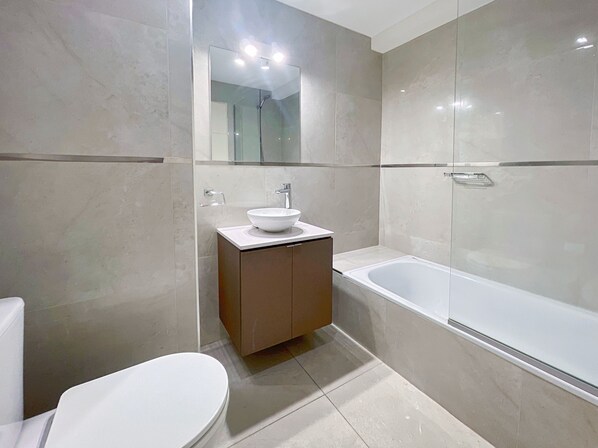 A modern bathroom with a white sink, a toilet, and a bathtub.