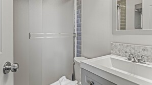 A bathroom with a shower, a sink, and a mirror. - 2 Bed |Sleeps 8|Walkout to Heated Pool|Hot Tub (Canmore)