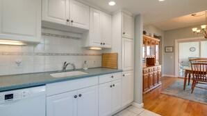 Eine moderne Küche mit weißen Schränken, einem Geschirrspüler von Bosch und einem Holzespeisetisch mit Stühlen.