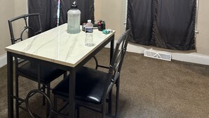Un espace repas comprenant une table, des chaises, un ventilateur de plafond et des rideaux.