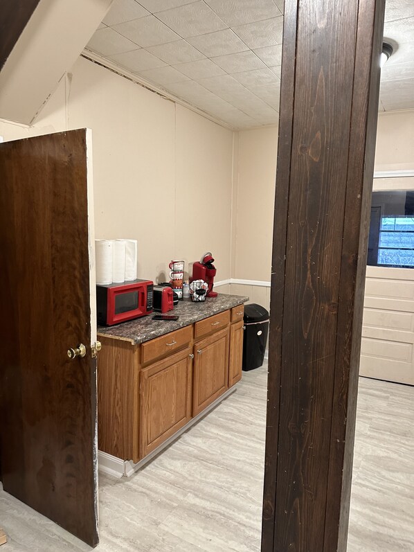 A kitchen with wooden cabinets, a countertop, and a microwave.