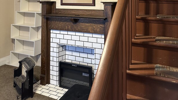 Un salon avec une cheminée, un escalier en bois et un tableau encadré au mur.