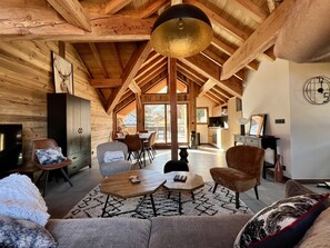 Een ruime loft met hoge plafonds, houten balken, een grote eettafel en een gezellige zithoek.