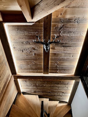 Een plafond met een houten balkenstructuur en een gewei van een hert in het midden.
